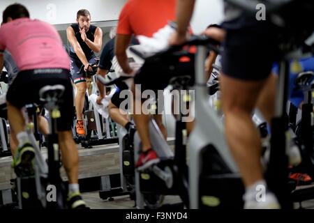 Istruttore di Fitness di fronte a persone di equitazione bicicletta stazionaria durante una lezione di spinning presso la palestra Foto Stock