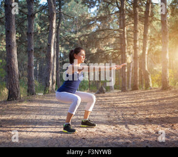 Giovane bella ragazza sport nella foresta di autunno al tramonto Foto Stock