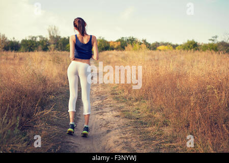 Giovane bella ragazza sport nella foresta di autunno al tramonto Foto Stock