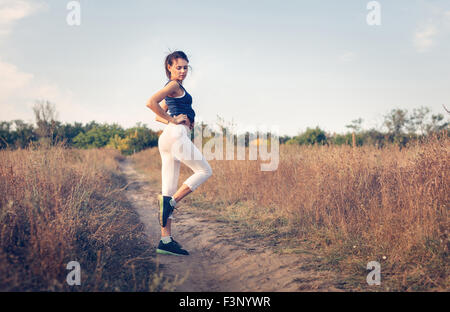 Giovane bella ragazza sport nella foresta di autunno al tramonto Foto Stock