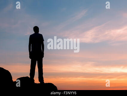 Silhouette di un uomo con sollevata in armi il bellissimo tramonto sulla montagna. Sfondo Foto Stock