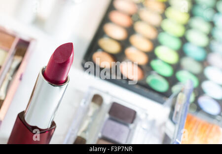 Rossetto rosso con sfocatura dello sfondo dei cosmetici come trucco e tavolozza arrossire su e lo spazio negativo per file Word e di testo. Foto Stock