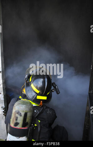 I vigili del fuoco con apparecchiature protettive in una piena di fumo camera Foto Stock