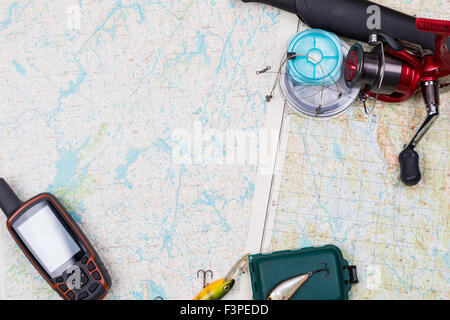 Preparazione in viaggio di pesca con la pesca affronta e gps navigator su sfondo mappa Foto Stock