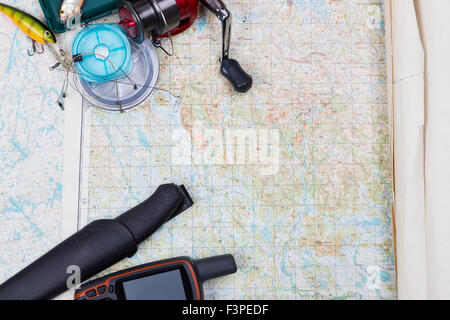 Preparazione in viaggio di pesca con la pesca affronta e gps navigator su sfondo mappa Foto Stock