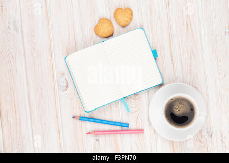 Caffè, a forma di cuore i cookie e blocco note su bianco tavolo in legno con spazio di copia Foto Stock