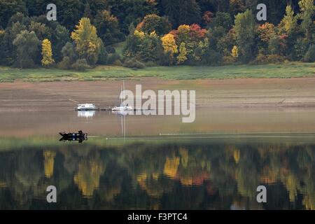 Waldeck, Germania. Il 7 ottobre, 2015. Un pescatore nella sua barca sul lago Edersee passa autunno gli alberi che si riflettono nel lago e alla superficie, vicino a Waldeck, Germania, 7 ottobre 2015. Foto: Uwe Zucchi /dpa/Alamy Live News Foto Stock