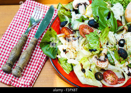 Fresca Insalata estiva con pomodori ciliegia, Spinaci, Rucola, romaine e lattuga in una piastra bianca su sfondo di legno, selettivo Foto Stock