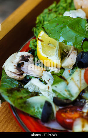 Fresca Insalata estiva con pomodori ciliegia, Spinaci, Rucola, romaine e lattuga in una piastra bianca su sfondo di legno, selettivo Foto Stock