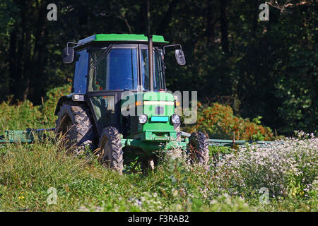 Trattore verde nel campo in una comunità agricola Foto Stock
