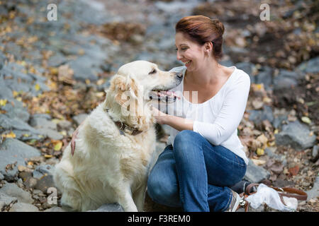 Donna seduta nella foresta con Labrador Foto Stock