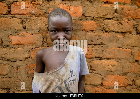 Ragazzo in piedi di fronte a un muro di mattoni di fango, Mozambico, Africa Foto Stock