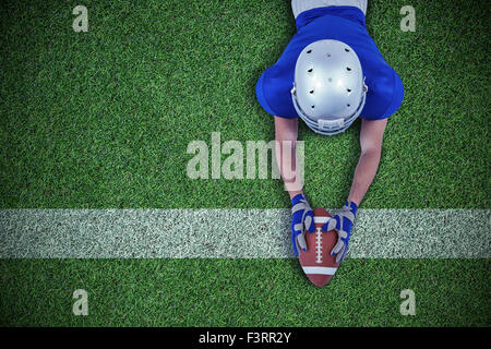 Immagine composita della vista posteriore del giocatore di football americano che si allunga verso la sfera Foto Stock