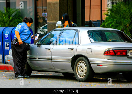 Una femmina di parcheggio del veicolo Enforcement officer emette un biglietto a un badge in Beverly Hills California Foto Stock