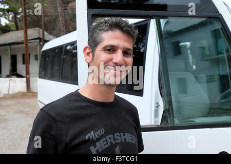Un bel cordiale giovane turista bus driver sorridente in piedi accanto a una gita in autobus a Cipro del Nord KATHY DEWITT Foto Stock