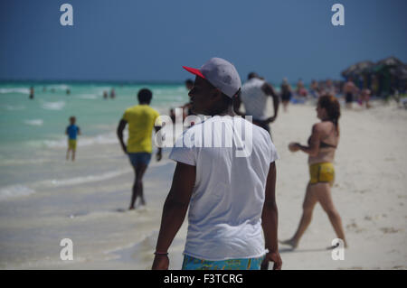 Gruppo di persone locali a piedi lungo il turista sulla spiaggia di Pilar, Cuba Foto Stock
