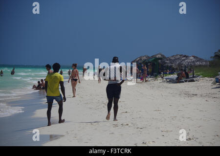 Gruppo di persone locali a piedi lungo il turista sulla spiaggia di Pilar, Cuba Foto Stock