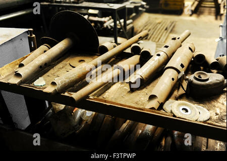 Rusty diversi utensili industriali su una tabella all'interno di una fabbrica Foto Stock