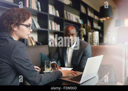 Giovane imprenditrice lavorando sul computer portatile con il suo partner commerciale mentre è seduto presso il cafe. Giovani dirigenti presso la caffetteria incontro f Foto Stock