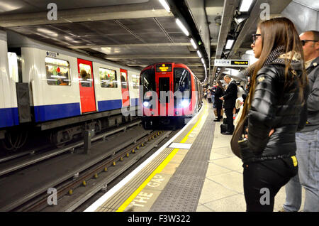 Londra, Inghilterra, Regno Unito. In attesa di un treno di tubo sulla piattaforma di Westminster stazione della metropolitana Foto Stock