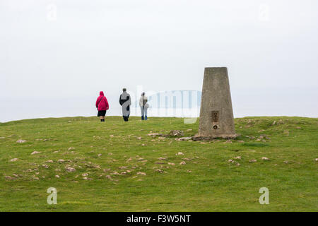 Le persone camminare davanti a un punto di innesco sul promontorio verso Brean giù forte lungo Brean giù, Somerset, Regno Unito. Foto Stock