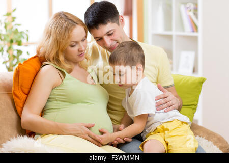 Famiglia aspettano di nuovo bambino. Little Boy toccando donna incinta pancia Foto Stock