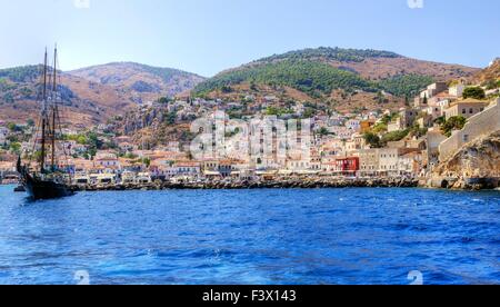 Una vista della bellissima isola greca, Hydra. Vi è una barca a vela in primo piano e alcune architettura locale sul backgr Foto Stock