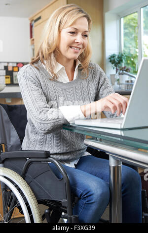 Donna disabile in carrozzina tramite portatile a casa Foto Stock