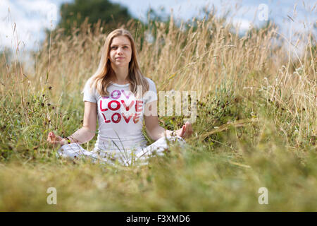 Ragazza giovane meditando nel campo Foto Stock