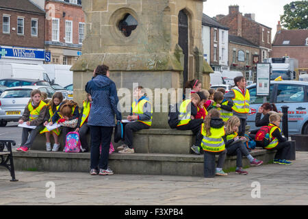 Un gruppo di bambini e insegnanti di una scuola gita presso la piazza del mercato Thirsk North Yorkshire Foto Stock