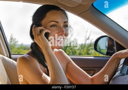 Donna conducente parlando al cellulare Foto Stock