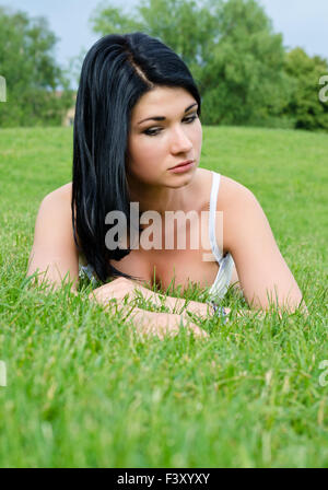 Bella pensieroso donna sdraiata sull'erba Foto Stock
