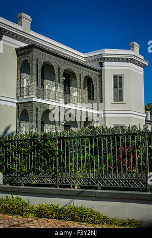 Vista sul marciapiede di una splendida mansion dietro una recinzione in ferro ornato di balconi di ferro nel Garden District di New Orleans, LA Foto Stock