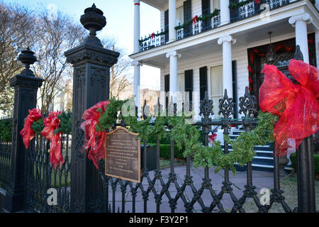 Nastro rosso legato attorno nero ferro battuto recinzione in parte anteriore della storica casa coloniale nel giardino del Distretto di New Orleans, LA Foto Stock