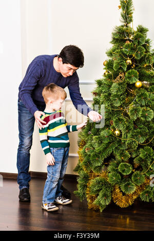Ragazzo decorare l'albero di natale con suo padre a casa Foto Stock