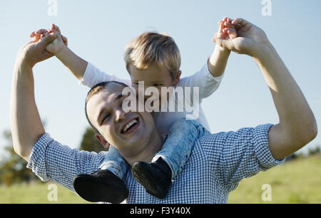 Papà dando il suo giovane figlio un piggy back ride Foto Stock