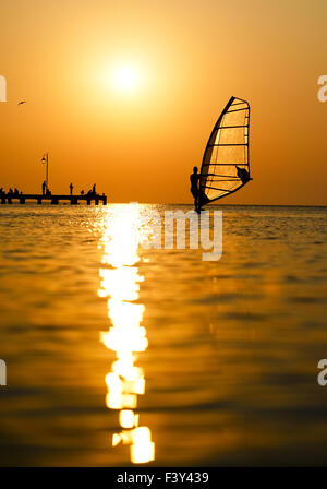 Silhouette di surfer al tramonto passando da Foto Stock