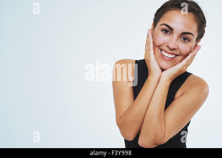 Bella donna con una bella pelle, sorridente in telecamera tenendo le sue guance. Copia dello spazio. Ritratto isolato Foto Stock