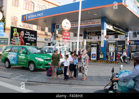 Il Vietnam benzina dalla stazione di Saigon, famiglia attendere per attraversare la strada a Saigon centro,Vietnam,Asia Foto Stock