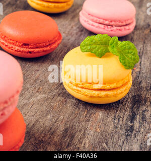 Alcuni appetitosi macarons con diversi colori e sapori su una tavola in legno rustico Foto Stock