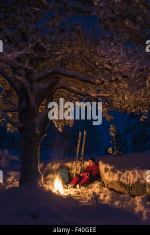 Sciatore accanto a un falò, Lapponia, Svezia Foto Stock