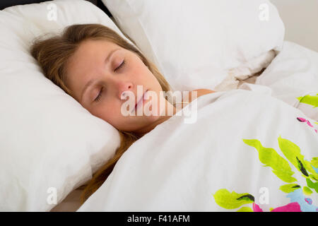 Giovane donna addormentata nel letto Foto Stock