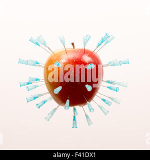 Una mela rossa piena di aghi ipodermici, isolato su sfondo bianco. Foto Stock