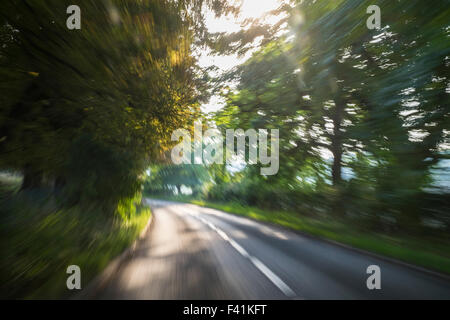 Accelerando giù per una strada di campagna visibile attraverso una finestra di auto Foto Stock