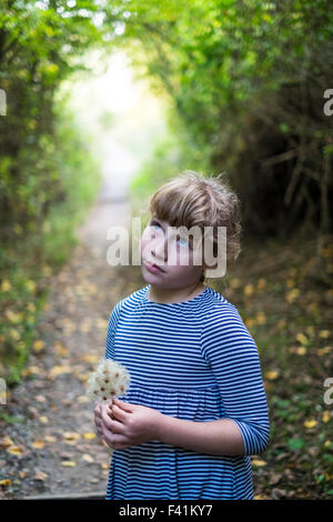11 anno vecchia ragazza guarda pensieroso nel bosco Foto Stock