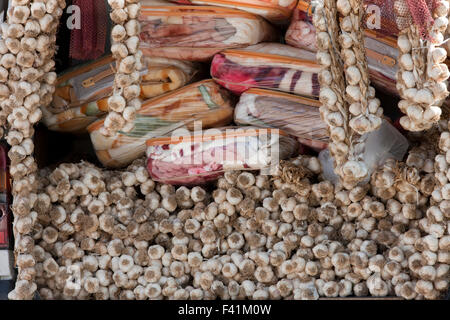 Primo piano di una pila di essiccato appeso spicchi di aglio per la vendita tra pacchi di coperte su uno zingaro Peddler's van. Foto Stock