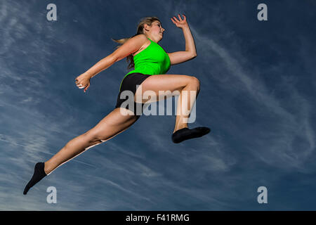 Giovane donna, 18 anni, saltando contro il cielo di sera Foto Stock