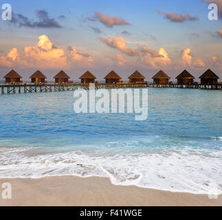 Villa su pali in acqua al momento del tramonto Foto Stock