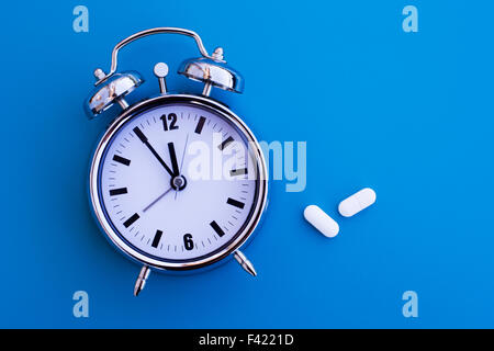 Sveglia sul tavolo blu con farmaci Foto Stock