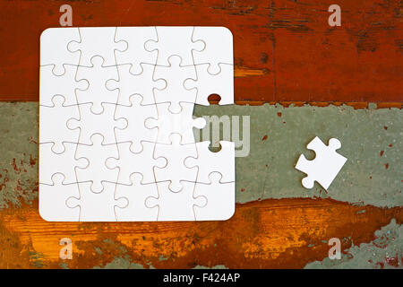 Puzzle di bianco con pezzo mancante sulla vecchia tabella vintage Foto Stock